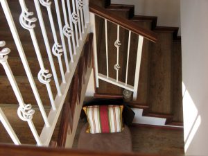 Natural wood stairs with white wrought iron railing